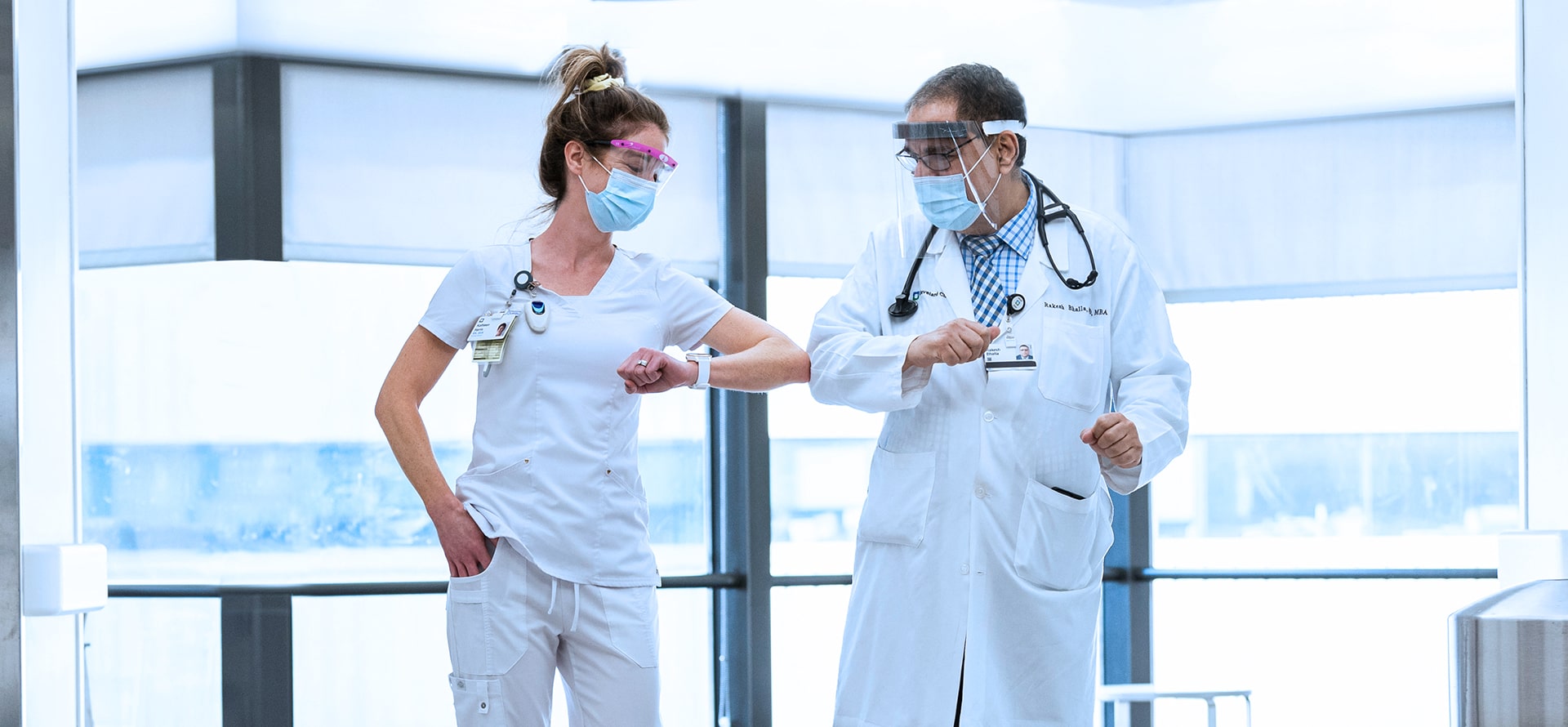 A masked nurse and doctor bumping elbows